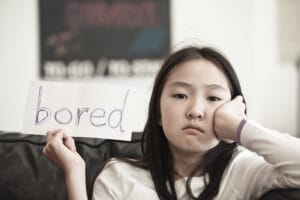 How to focus your story so you don't wear out your welcome. A girl holding up a sign that says "Bored."