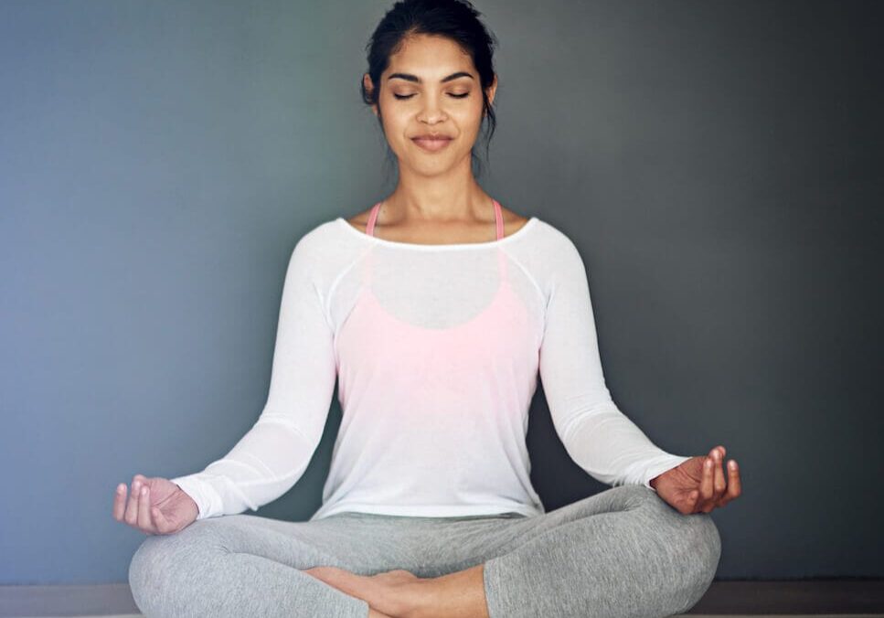 A yoga practitioner sitting cross-legged on a mat with eyes closed